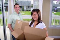 A happy couple holding moving boxes inside their new home, symbolizing a seamless relocation experience with a reliable packers movers company.